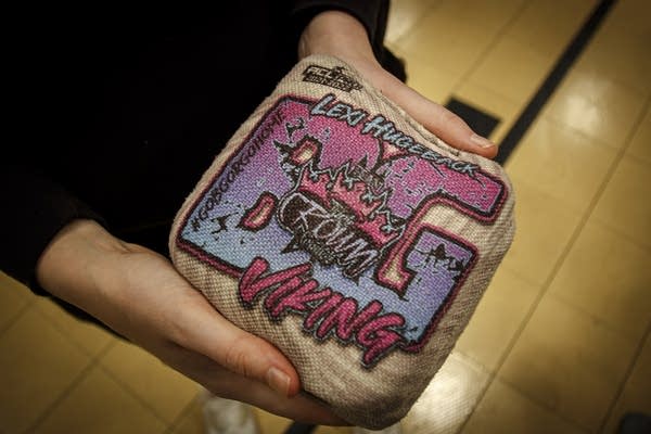 A person holds a decorated cornhole bag