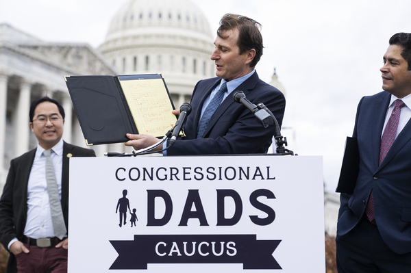 Rep. Dan Goldman, D-N.Y., holds up a note from his daughter as Reps. Andy Kim, D-N.J., (left) and Jimmy Gomez, D-Calif., look on during a news conference to announce the Congressional Dads Caucus outside the U.S. Capitol on Thursday. The group will advocate for issues such affordable child care, paid family leave and expansion of the Child Tax Credit.