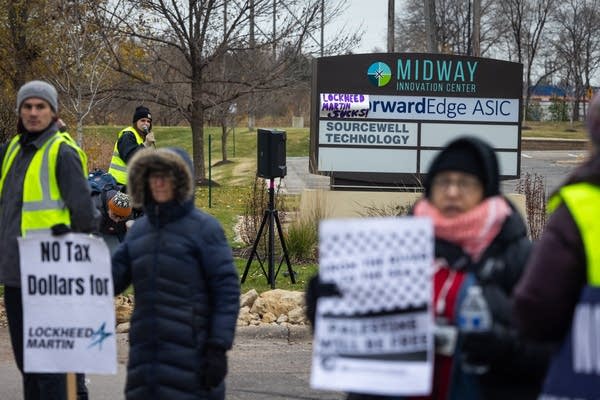 People hold signs and banners in a driveway