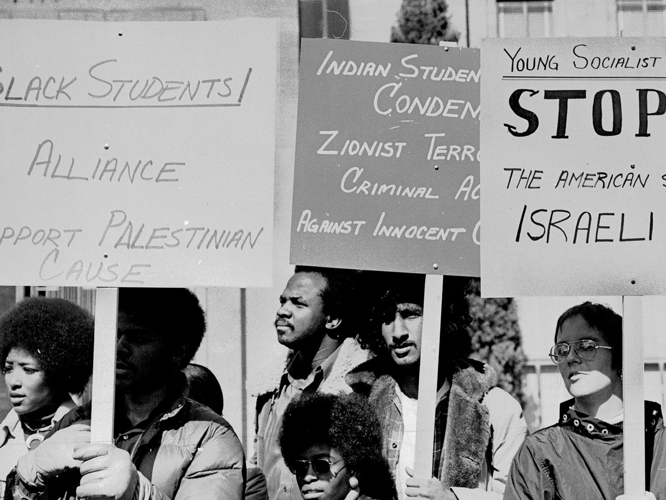 A black-and-white photo shows a group of students marching with handmade signs.