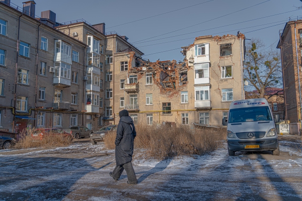 Woman walks in front of the damaged residential building in Sumy on 9 Feb 2025 Images: @shtukaanton - Anton Shtuka/NPR