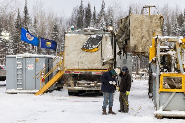 two people operate drilling equipment