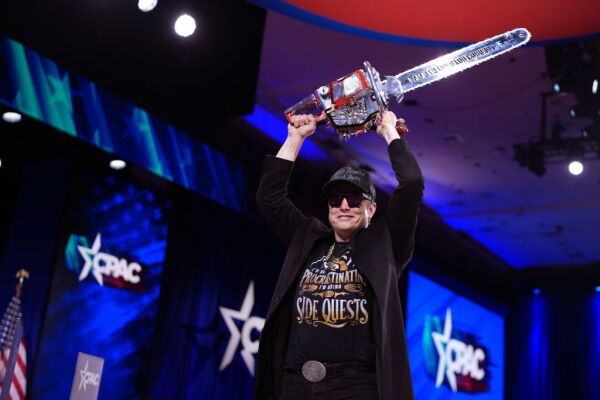 Elon Musk holds a chainsaw that was gifted to him at the Conservative Political Action Conference at the Gaylord National Resort Hotel And Convention Center on Thursday in Oxon Hill, Md.