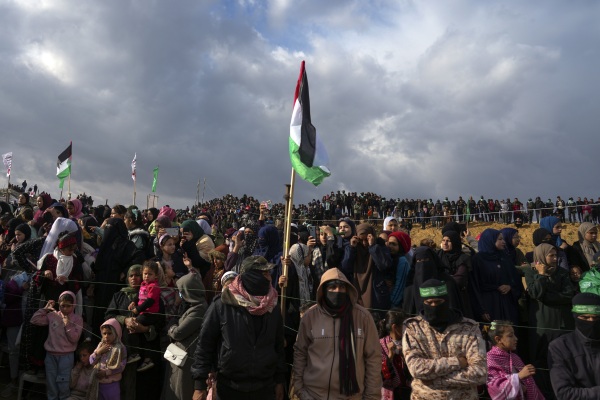 Palestinians gather as Hamas fighters deploy ahead of handing over the bodies of four Israeli hostages, including a mother and her two children, who had long been feared dead, to the Red Cross in Khan Younis, southern Gaza Strip on Thursday.