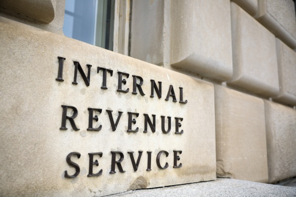 This photo shows a close-up of an exterior wall of the IRS building in Washington, D.C. Affixed on one part of the wall are black capital letters that say "Internal Revenue Service."