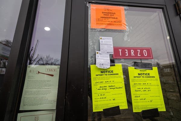 Notices are taped on the door of a restaurant