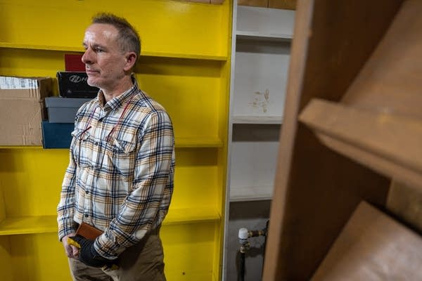 A man stands next to empty bookshelves