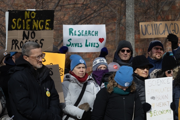 People carry homemade signs. One reads "Research saves lives"; another says, "No Science, No Progress."