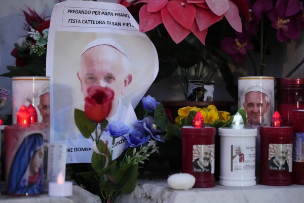 Candles are seen near pictures of Pope Francis outside the Agostino Gemelli Polyclinic in Rome, on Sunday, where the Pontiff is hospitalized since Feb. 14.