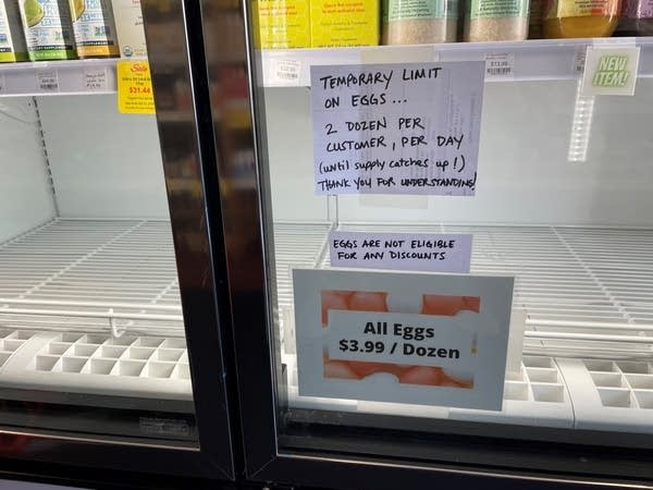 A woman stands near a grocery fridge display.