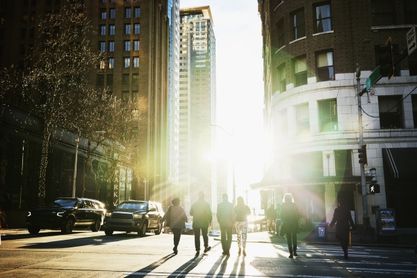 Wide shot rear view of business people crossing downtown street during evening commute