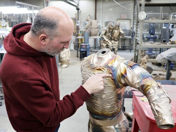 a man points to a bronze sculpture