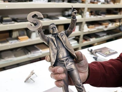 a man holds a small bronze figure