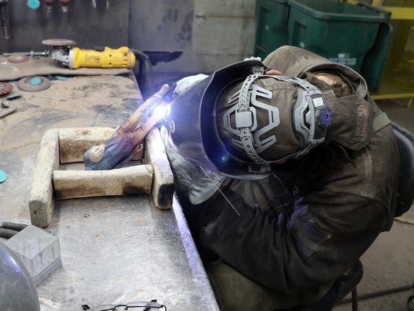 a man with a face shield uses a welder