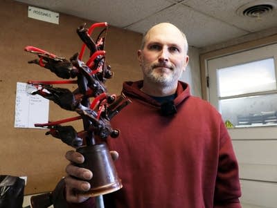 a man holds several small figurines 