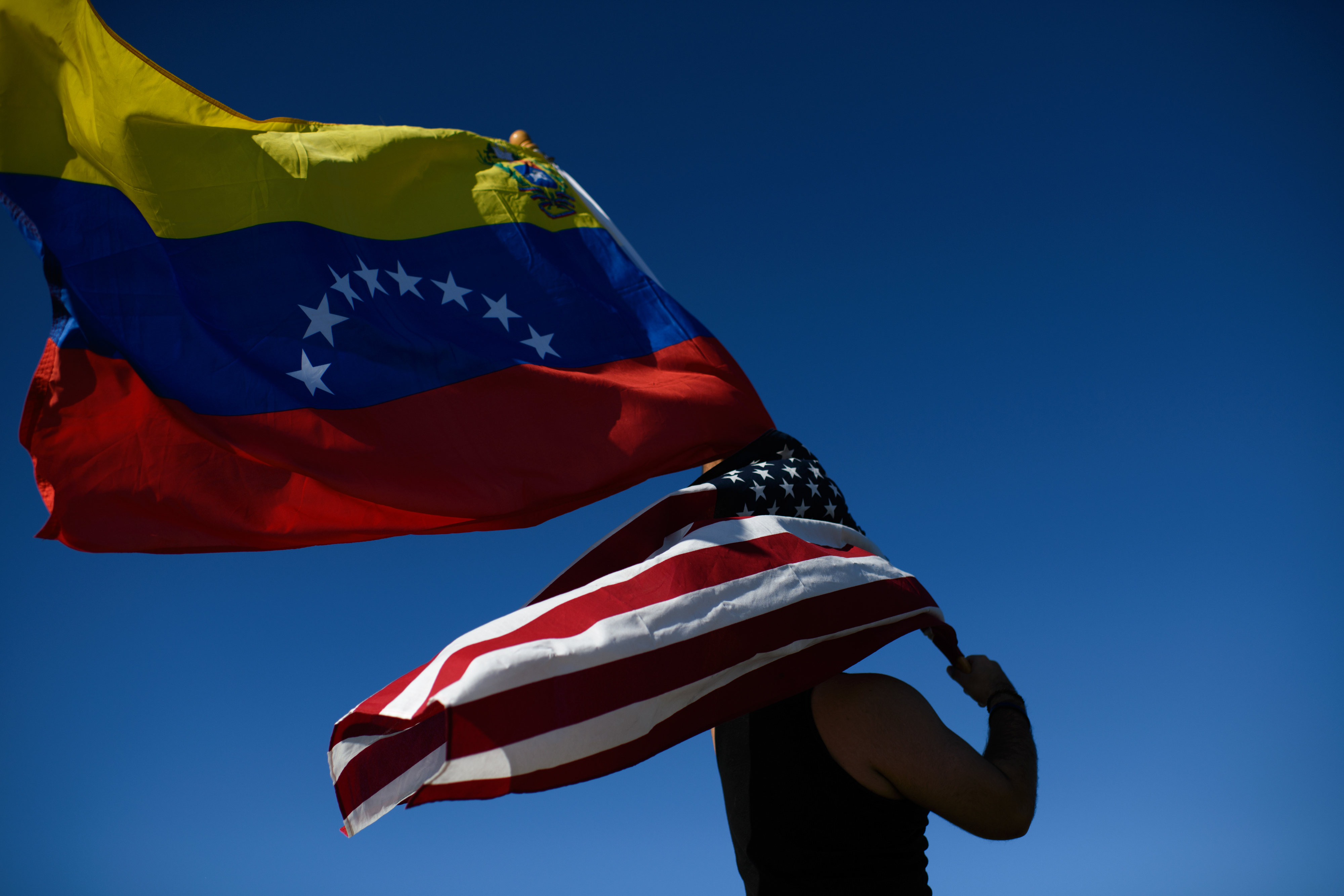 US and Venezuelan flags held by a demonstrator.