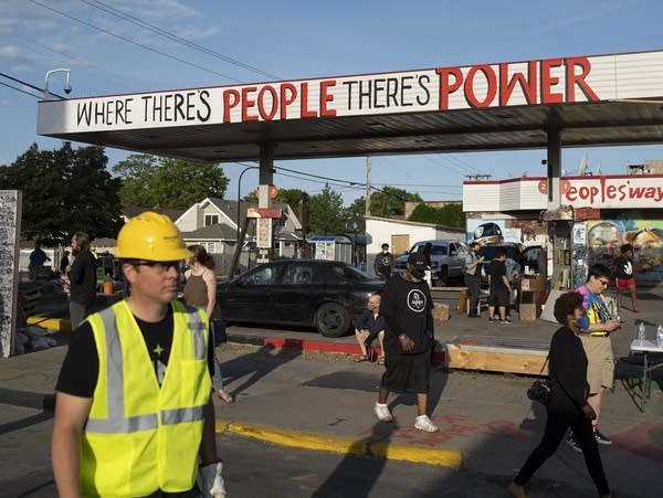 A city worker and residents walk in the street.