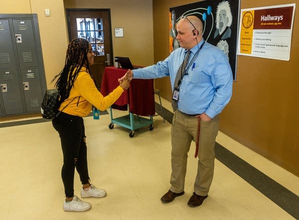 A principal shakes hands with a student.