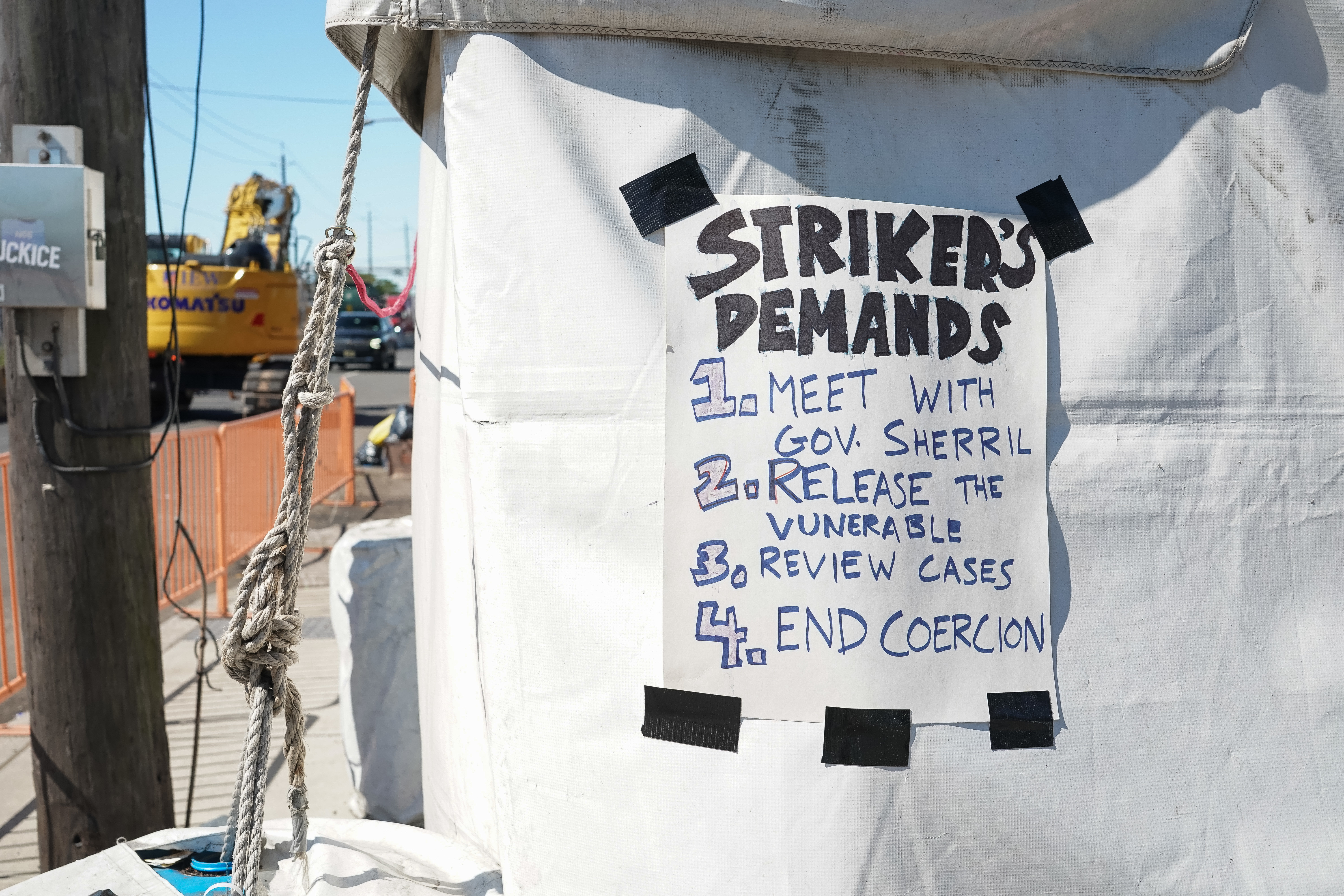 A sign listing strike demands is taped to a tent outside a detention center.