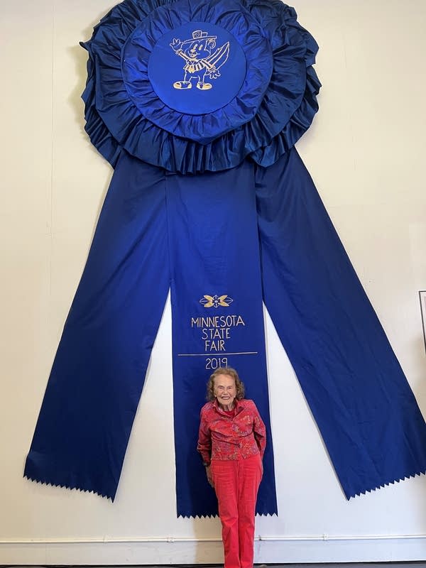 Woman stands in front of giant blue ribbon