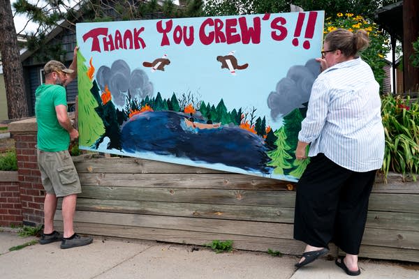 Two people installing a thank you firefighters sign