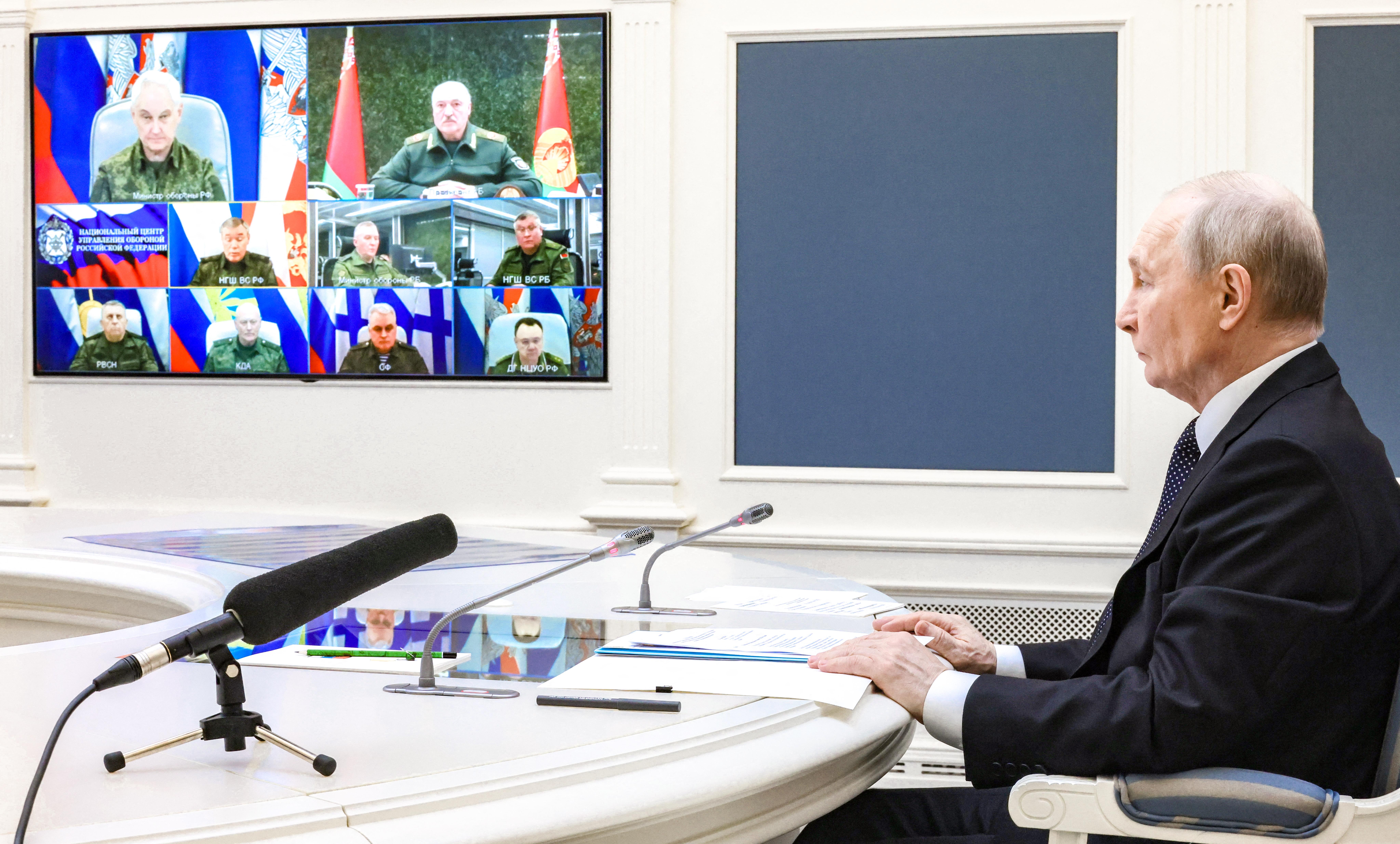 Putin speaks with military commanders on a video screen. 