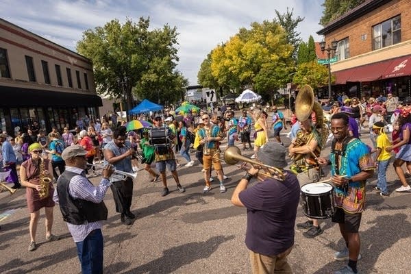 A crowd plays music and dances in the street.