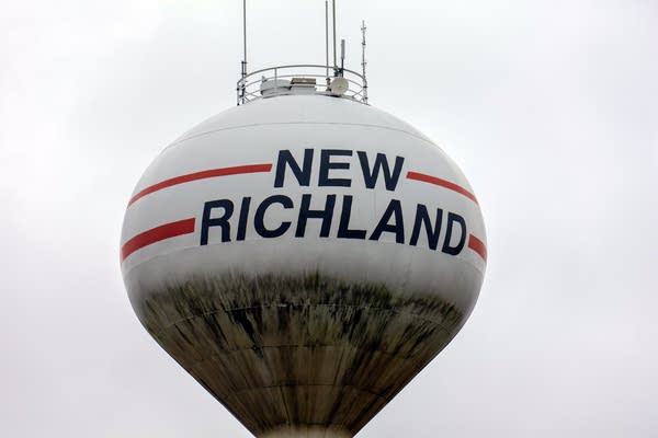 A white water tower with "New Richland" in dark blue font.