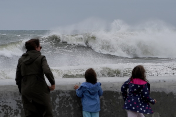 Spectators watch wave break during a nor'easter storm on Saturday in Hampton, N.H.
