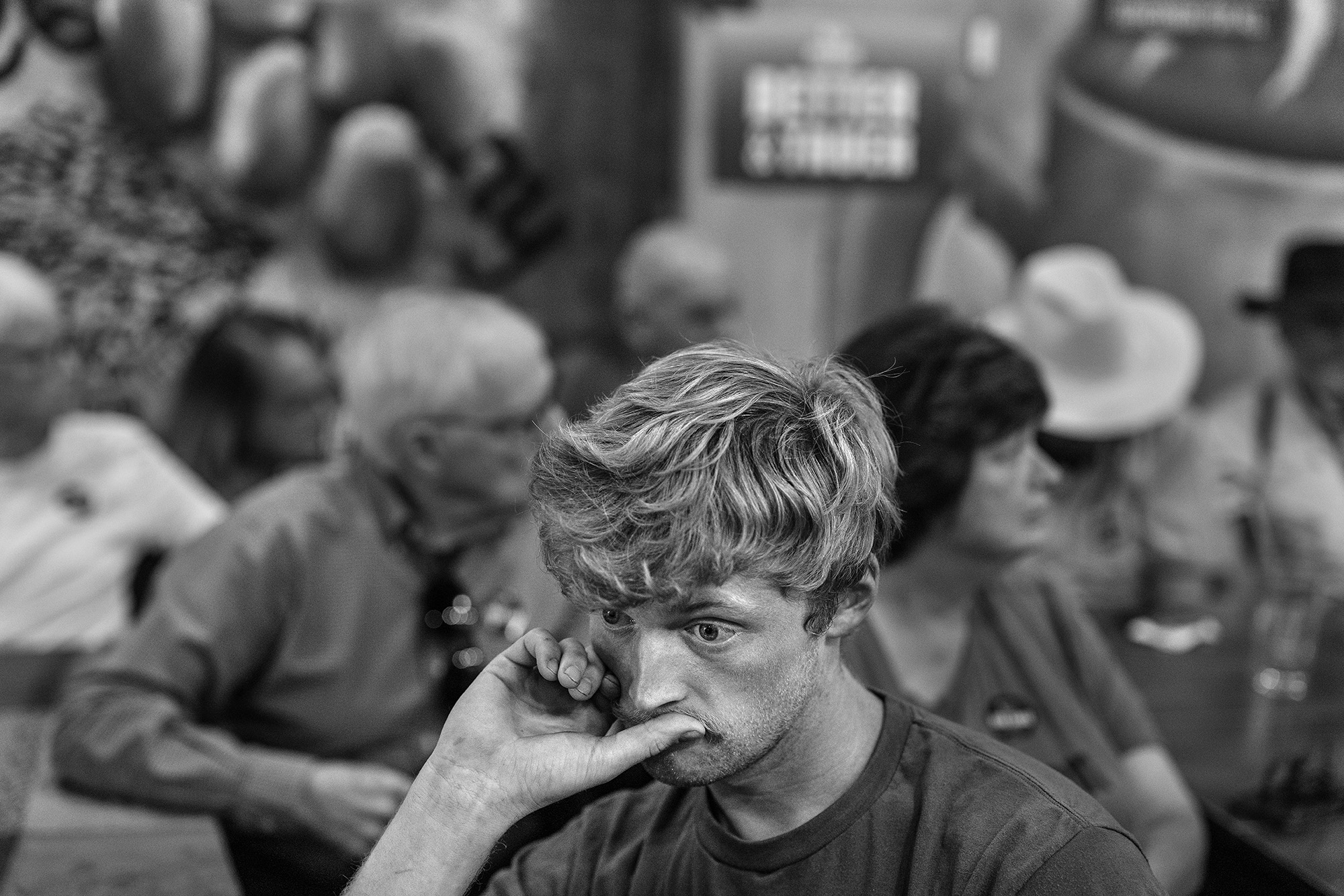 Man stares off with his thumb to his mouth.