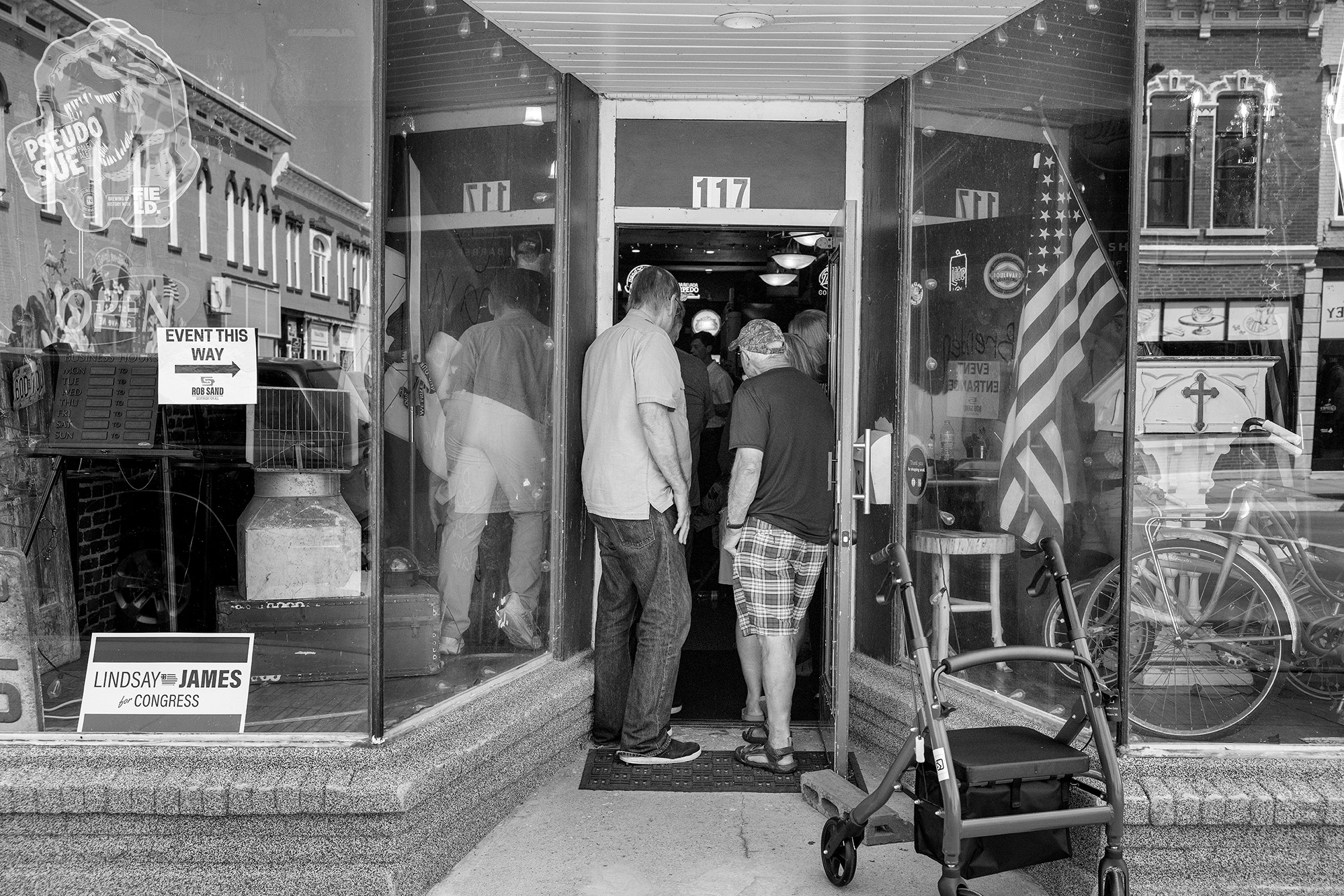 Two men stand in the door way of a store crowded with people.