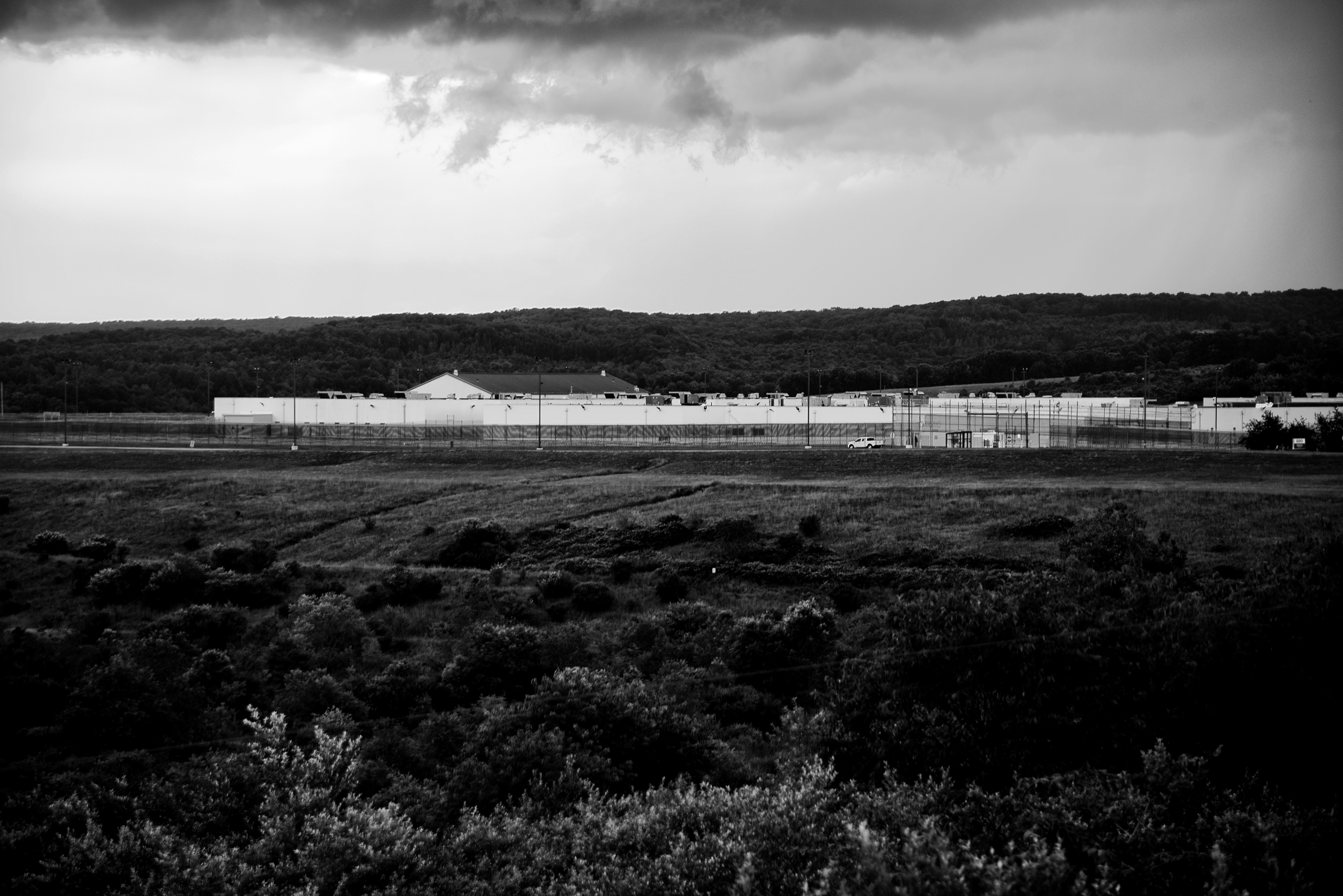 Prison facility seen in the distance of an otherwise empty field.