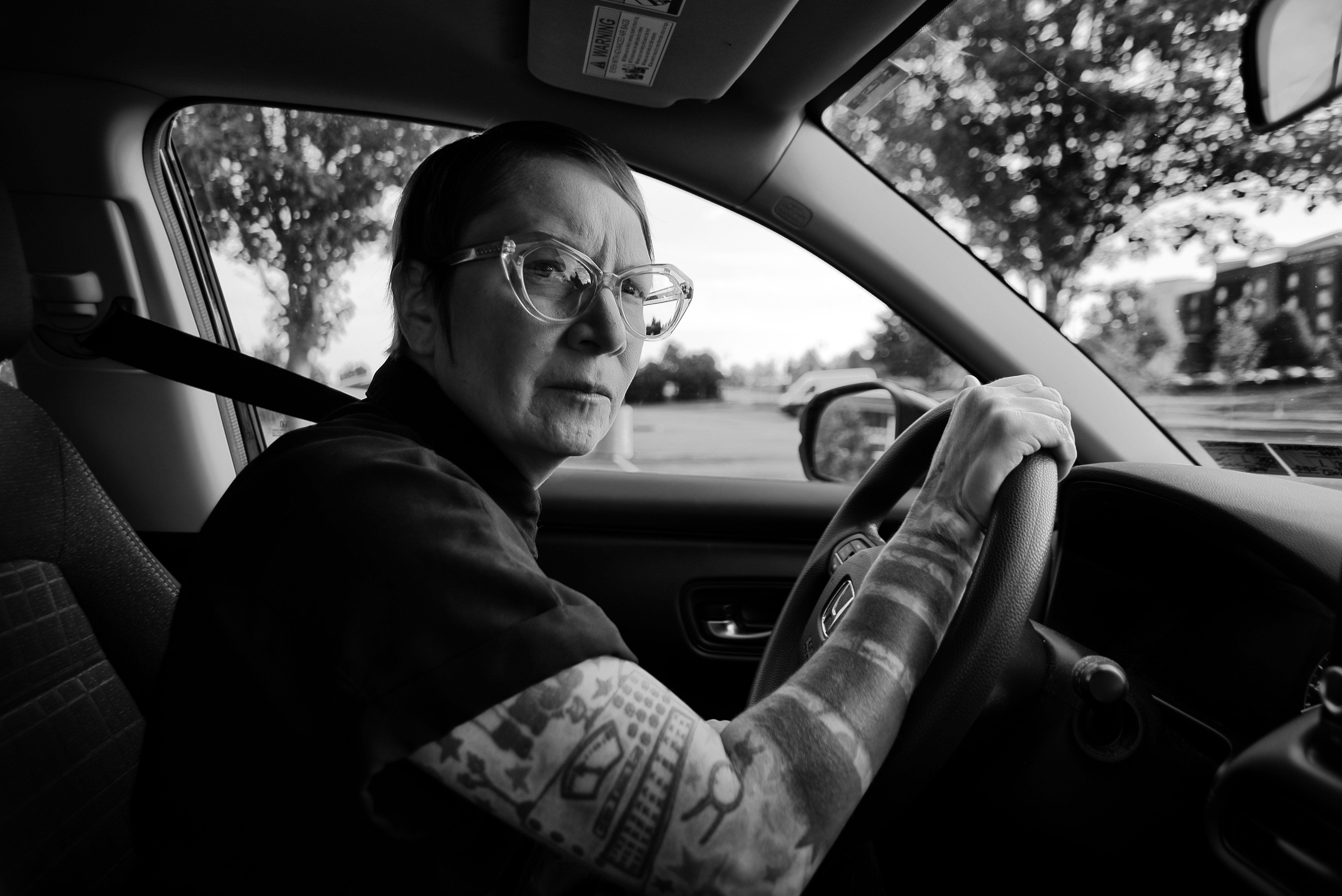 Woman wearing glasses driving a car.