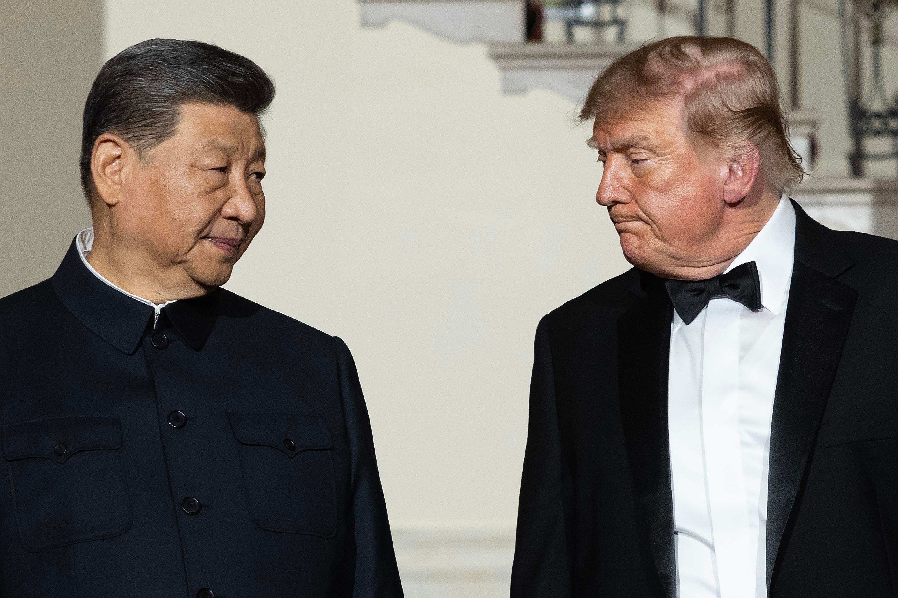 Chinese President Xi Jinping, left, and US President Donald Trump, right, both wearing formalwear, stand side by side, turned slightly toward each other.