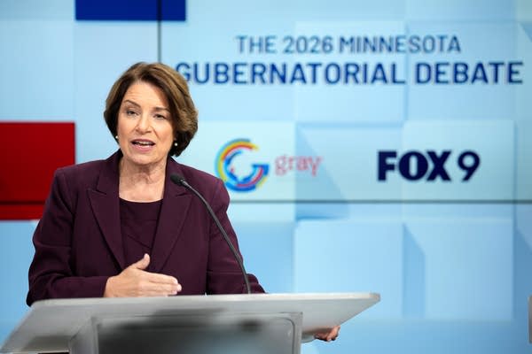 woman in purple speaks behind a podium