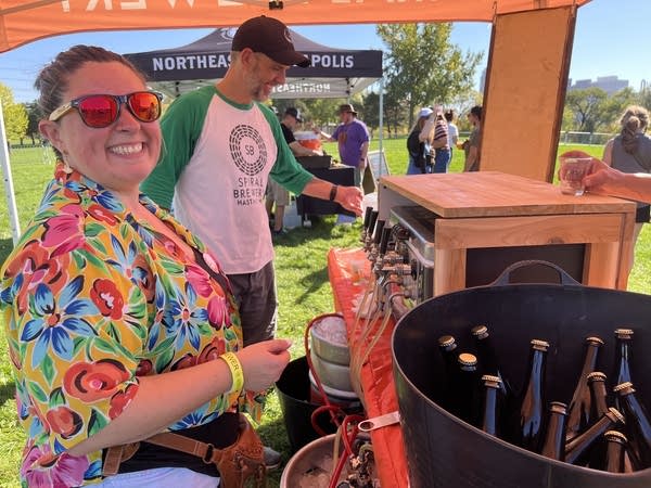 Two people behind a brewery set-up at a beer festival.