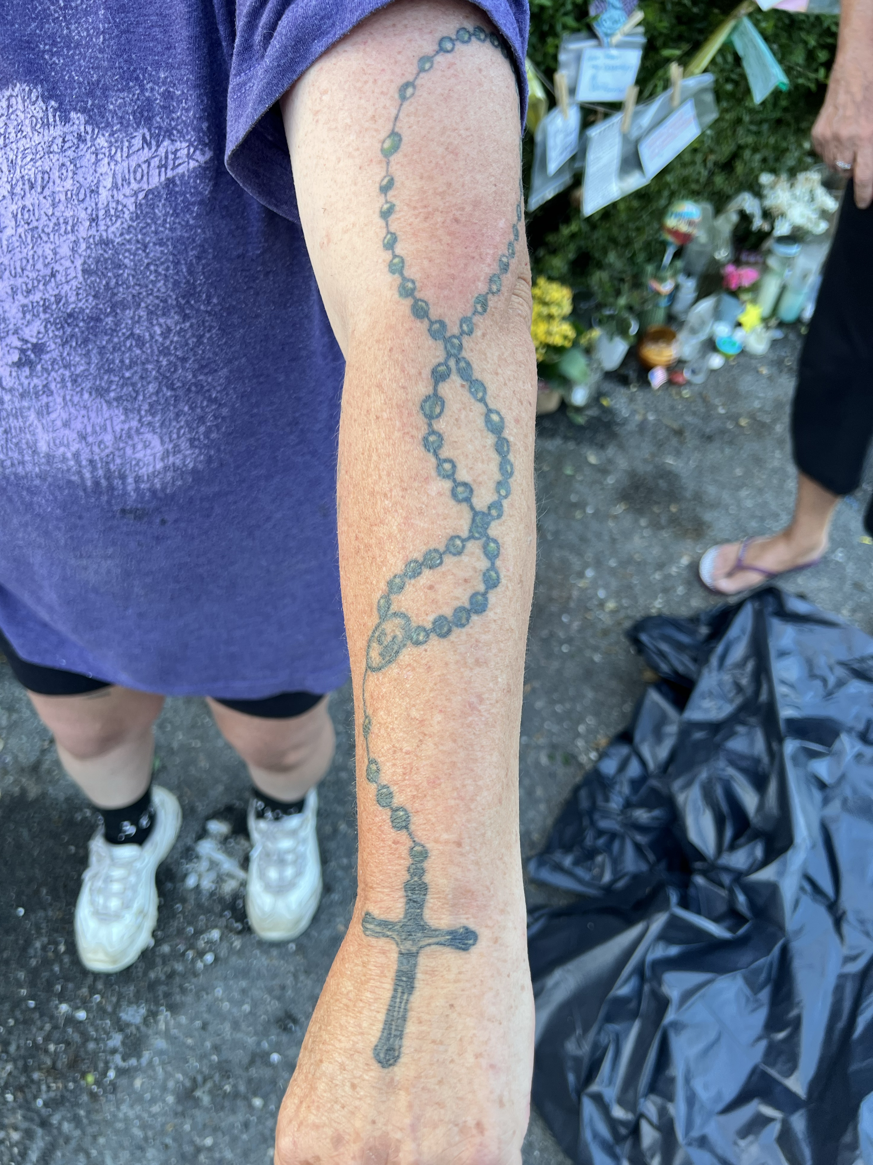 A woman shows a rosary tattoo that stretched from her hand up to her shoulder.