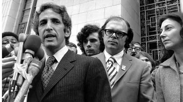 Black and white photo of white men in suits talking to the press on the courthouse steps
