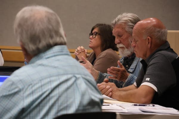 A group of school board members sit at a table for a meeting.