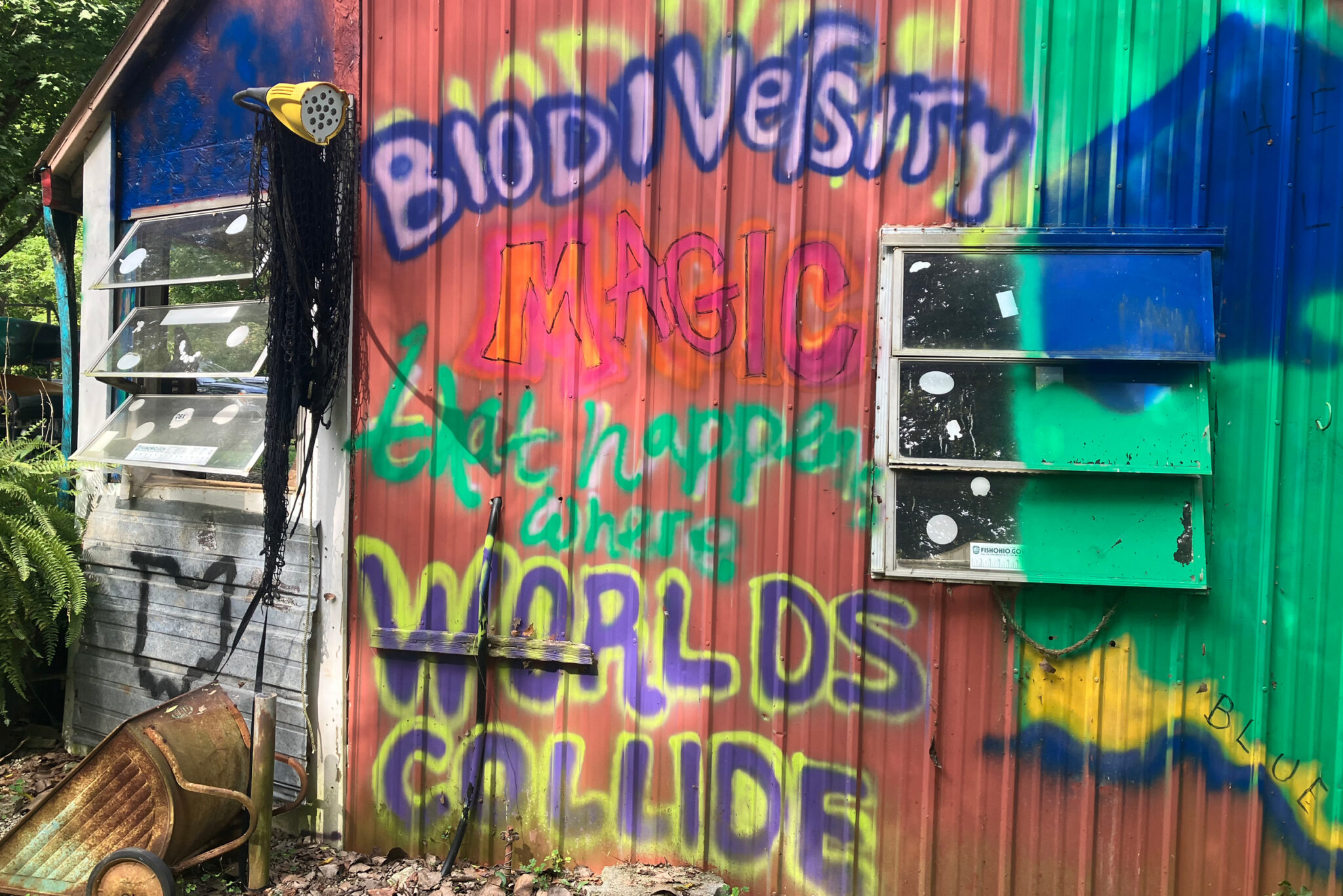 The colorful side of a building is painted with the words, “biodiversity magic that happens where worlds collide.”