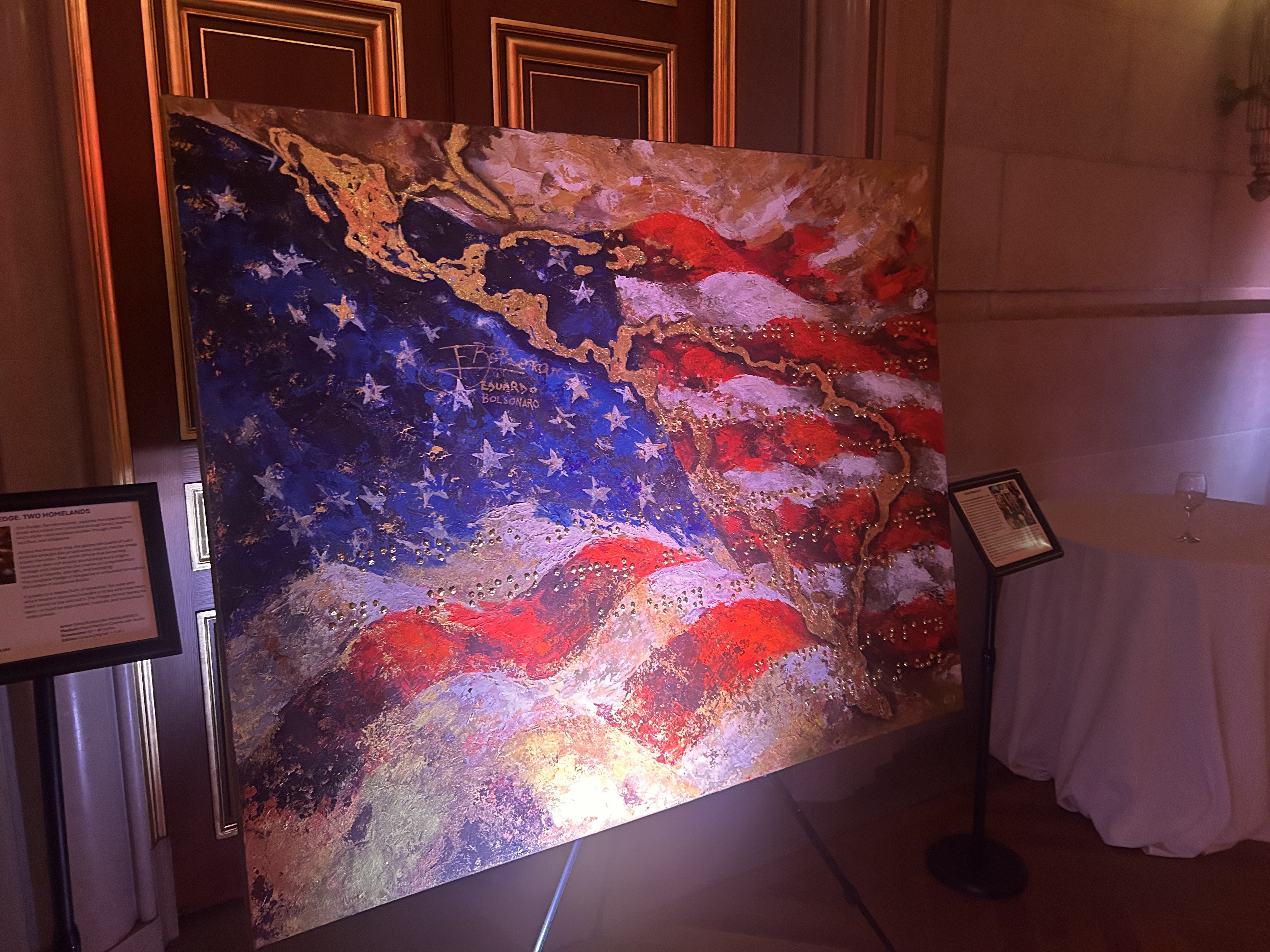 A painting of an American flag with the contour of Latin America in gold