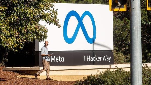 A man walks past the Meta logo. 