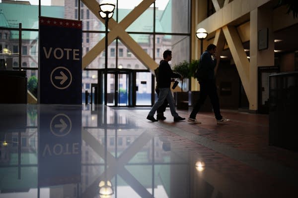Voters walk through an office lobby in front of signs directing them to voting booths.