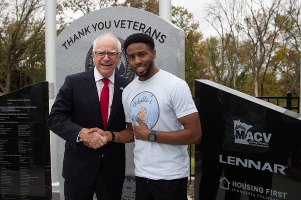 Two people posing for photo by a thank you veterans sign