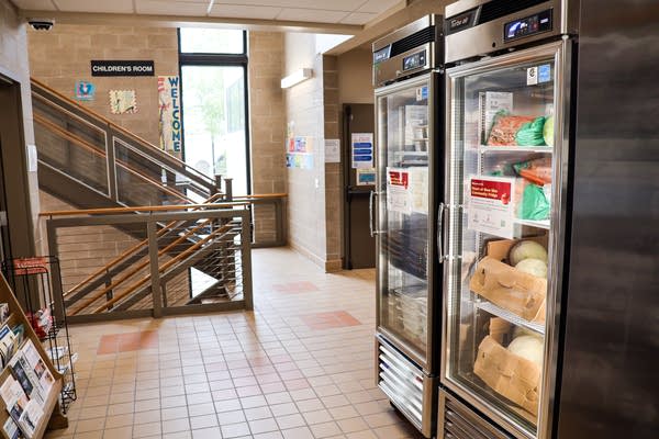 A fully stocked refrigerator stands next to a staircase in a library.
