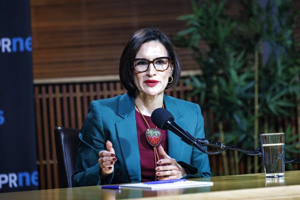 A woman sits in front of a microphone for a debate.