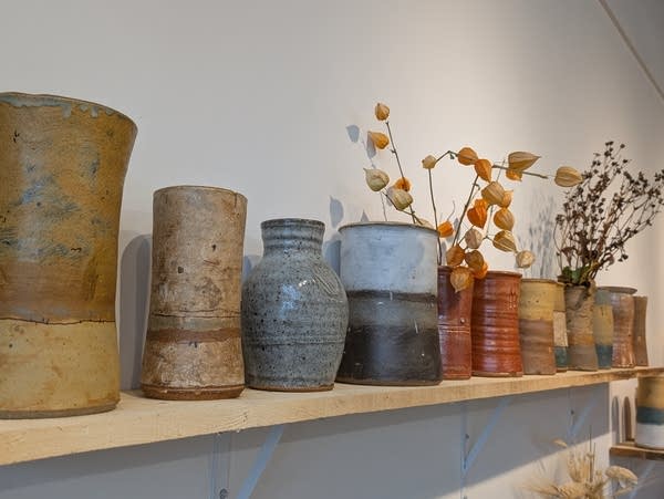 A shelf of pottery on a wall.