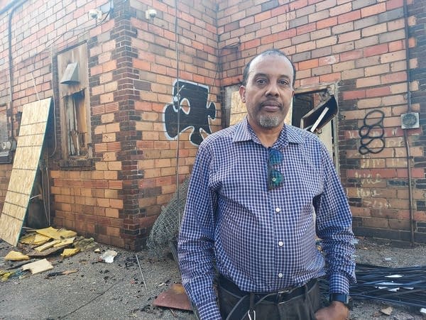A man stands outside a building damaged by a fire
