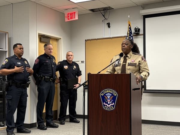 A sheriff speaks into a microphone at a podium in a conference room.